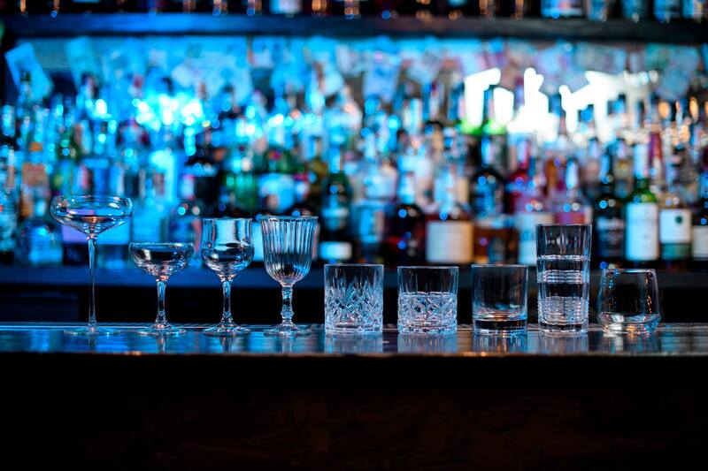 assortment of glassware from a bar with blue lighting in the background