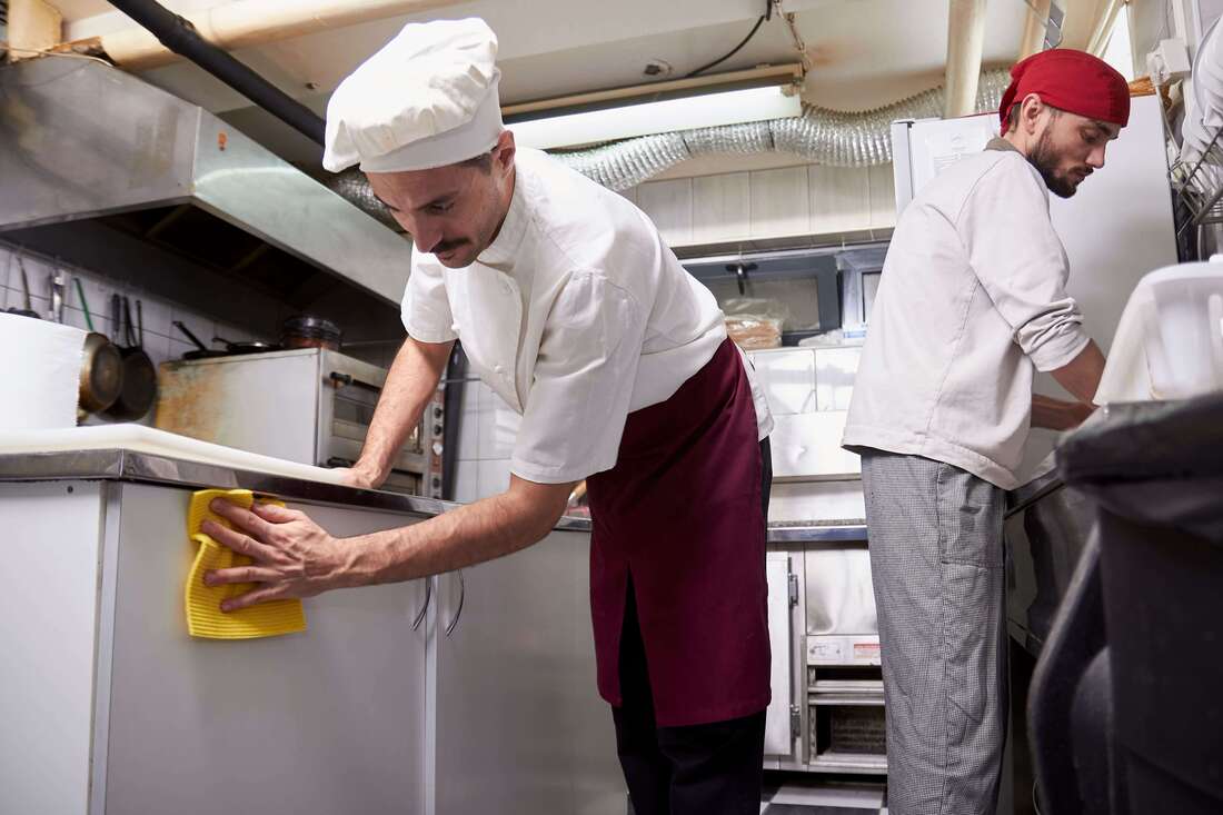 Chefs cleaning areas according to the restaurant kitchen cleaning requirements